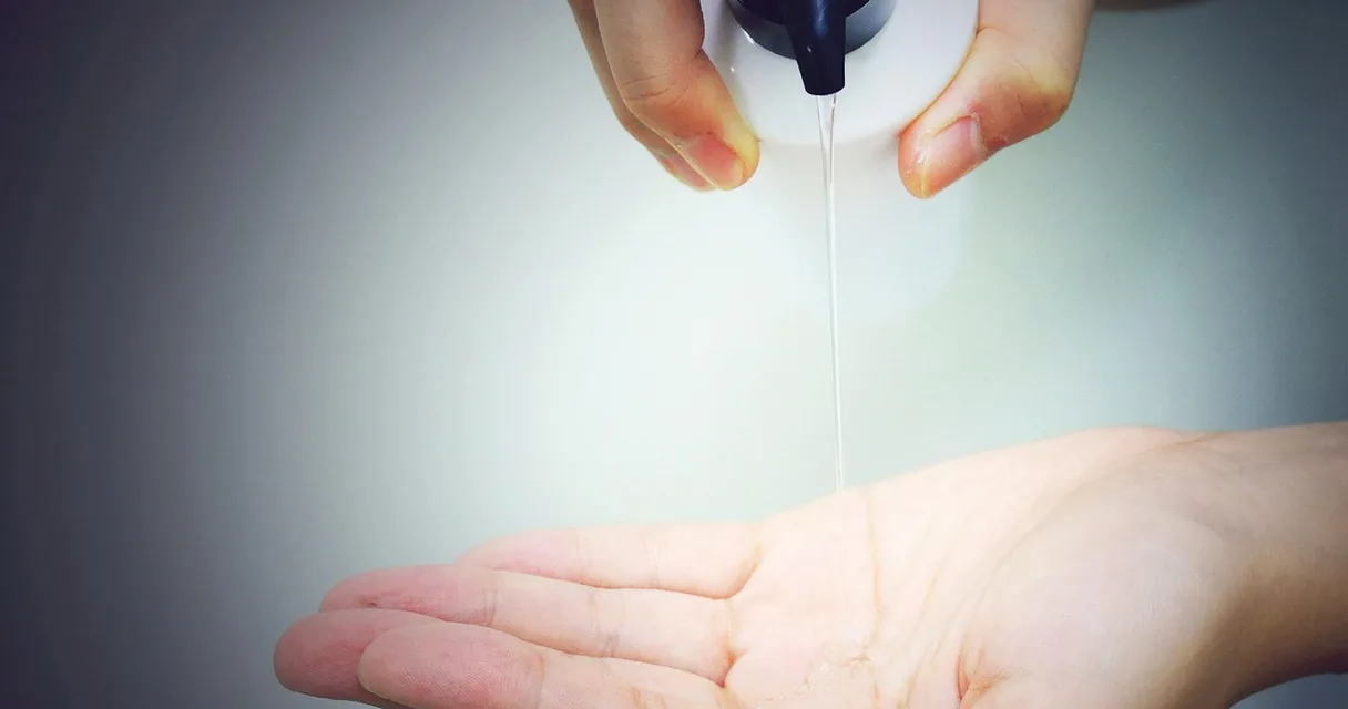 Mão recebendo xampu de um frasco com dispensador, ilustrando a queda de cabelo ao emagrecer rápido